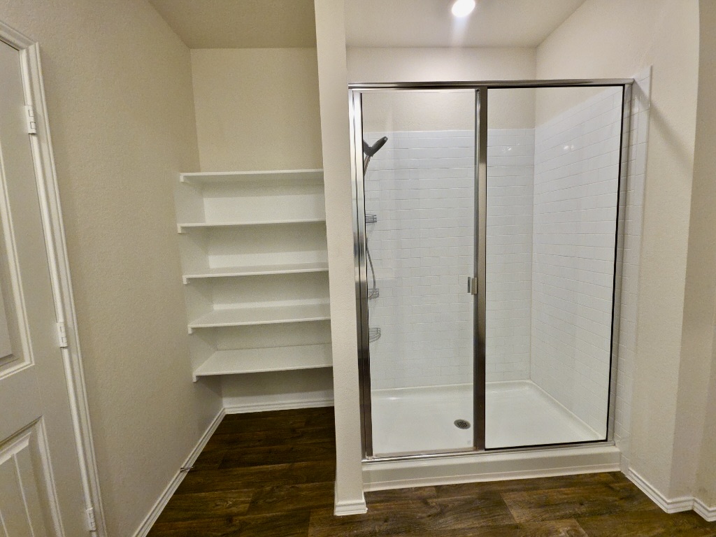 13525 Open Wagon Trail Elgin, TX 78621 - Photo 14 of 26 Full bathroom with a stall shower and dark wood-style flooring