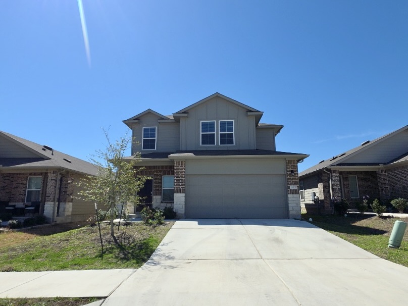 13525 Open Wagon Trail Elgin, TX 78621 - Photo 2 of 26 View of front of house featuring board and batten siding, a garage, concrete driveway, and brick siding