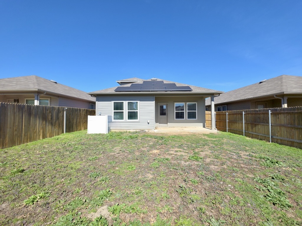 13525 Open Wagon Trail Elgin, TX 78621 - Photo 25 of 26 Rear view of house with a patio area, roof mounted solar panels, and a fenced backyard