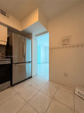 a view of a refrigerator in kitchen and an empty room