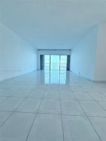 a view of an empty room with window and chandelier fan