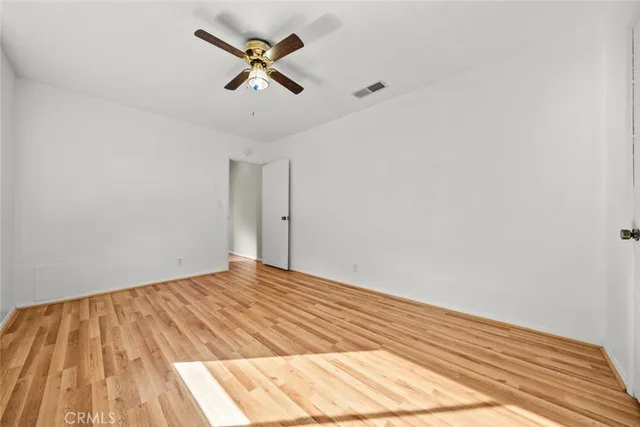 a view of a room with wooden floor and a ceiling fan