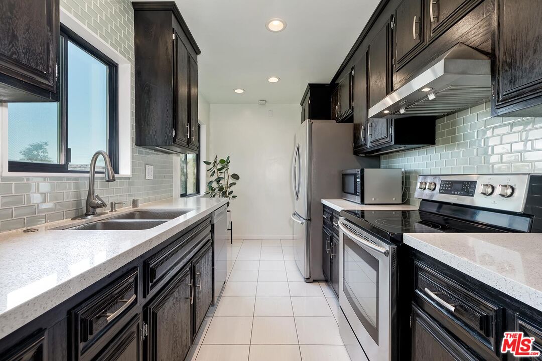 1045 North Kings Road, Unit 310 West Hollywood, CA 90069 - Photo 7 of 14 a kitchen with stainless steel appliances granite countertop a sink a stove and a refrigerator