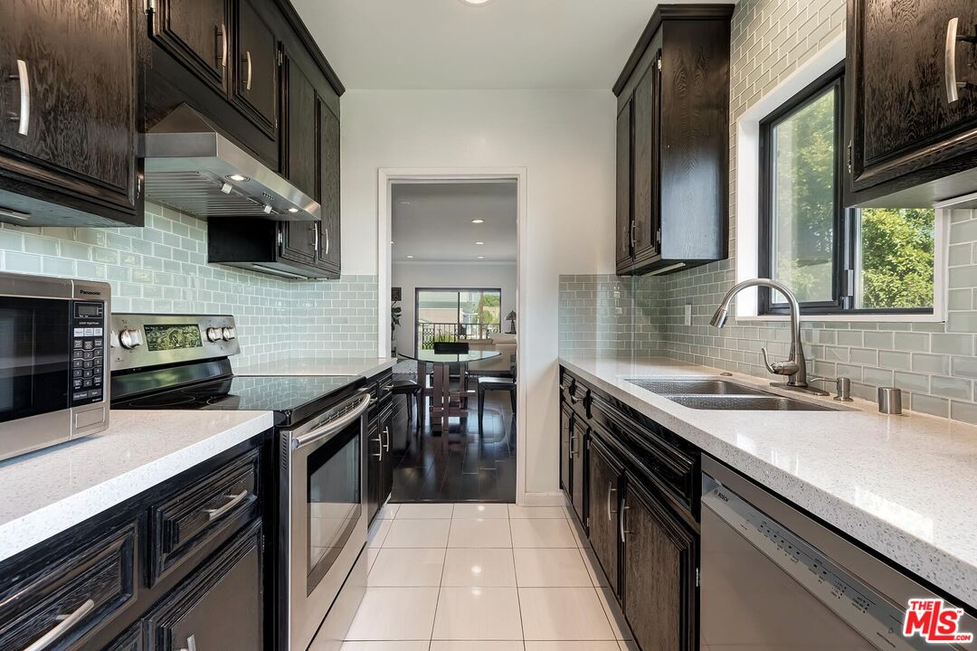 1045 North Kings Road, Unit 310 West Hollywood, CA 90069 - Photo 8 of 14 a kitchen with stainless steel appliances sink stove microwave and cabinets