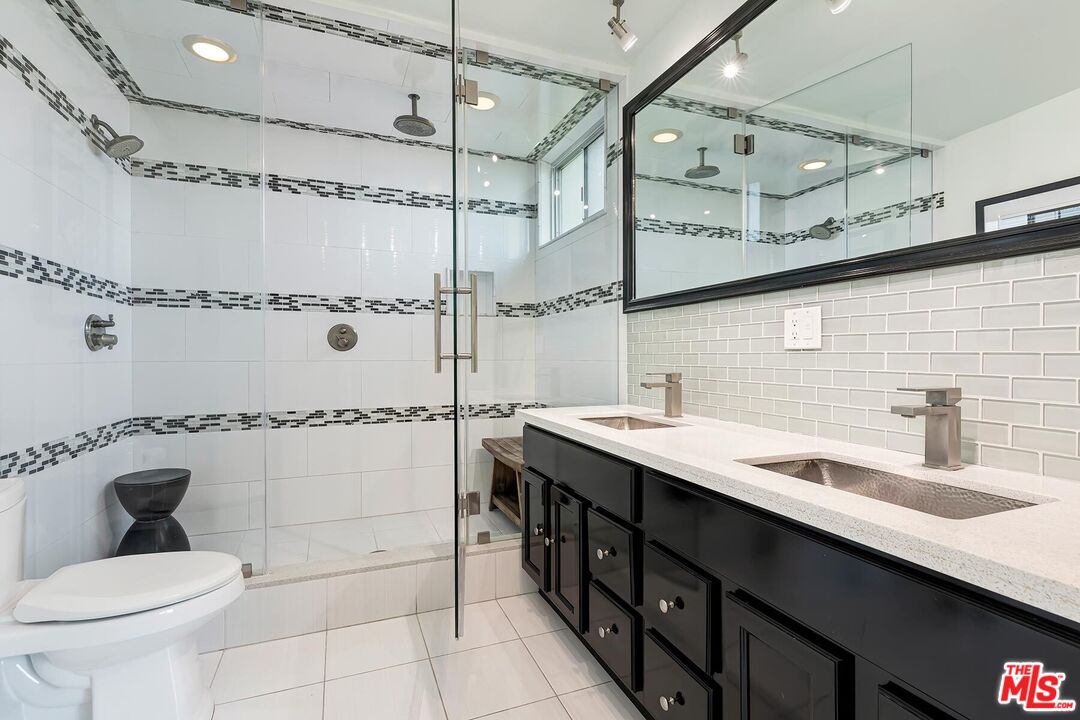 1045 North Kings Road, Unit 310 West Hollywood, CA 90069 - Photo 10 of 14 a bathroom with a double vanity sink toilet mirror and shower