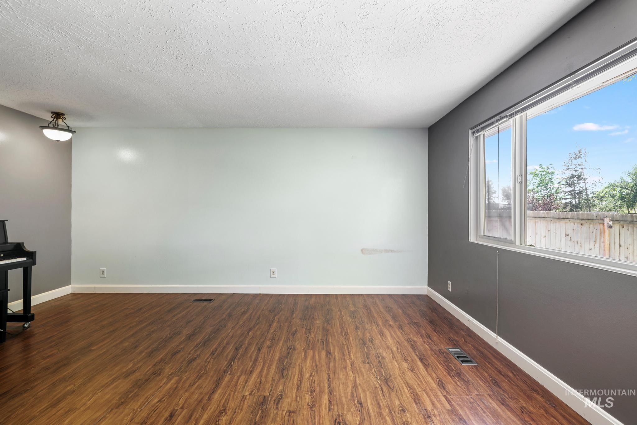 712 Locust Street Kimberly, ID 83341 - Photo 6 of 26 Spacious interior featuring wood-finish flooring, neutral gray walls, and multiple windows providing natural light