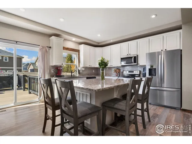 a kitchen with kitchen island a dining table chairs stainless steel appliances and cabinets