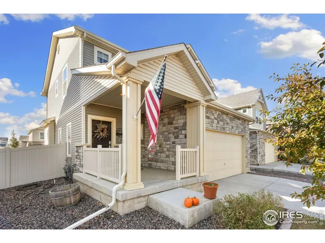 a view of a white house with a small yard and potted plants