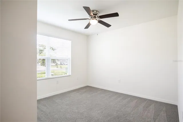 an empty room with a window and a fan