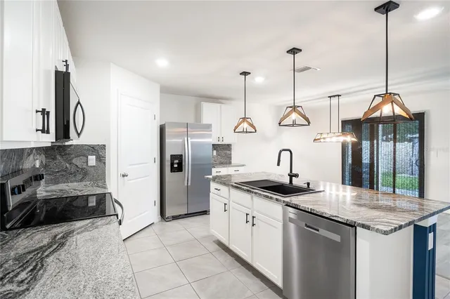 a kitchen with stainless steel appliances granite countertop a sink a stove and a refrigerator