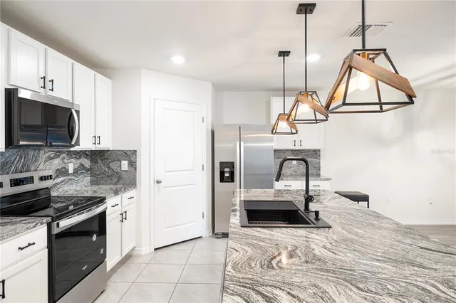 a kitchen with stainless steel appliances granite countertop a stove a sink and a refrigerator