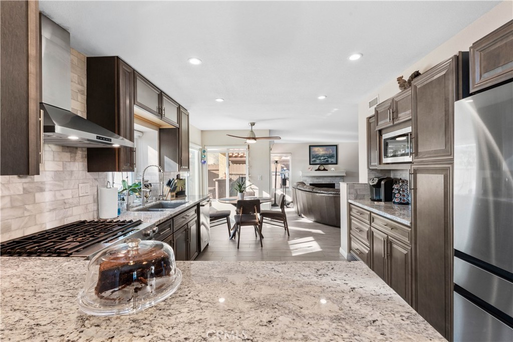 10963 San Mateo Place Rancho Cucamonga, CA 91701 - Photo 15 of 37 a kitchen with stainless steel appliances granite countertop a refrigerator stove oven a sink dishwasher a dining table and chairs with wooden floor