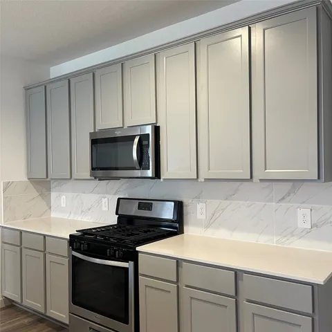 a kitchen with stainless steel appliances granite countertop white cabinets and a stove