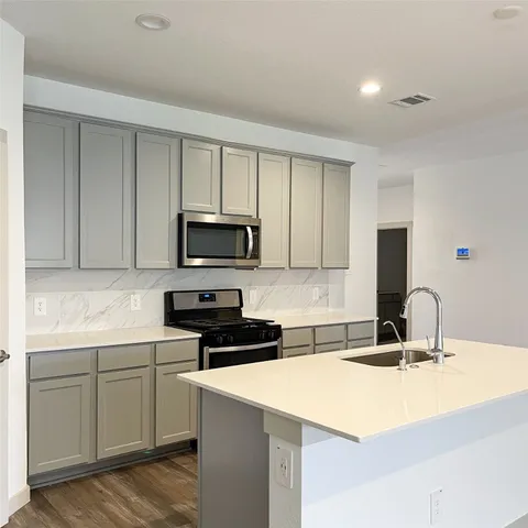 a kitchen with sink a microwave and cabinets