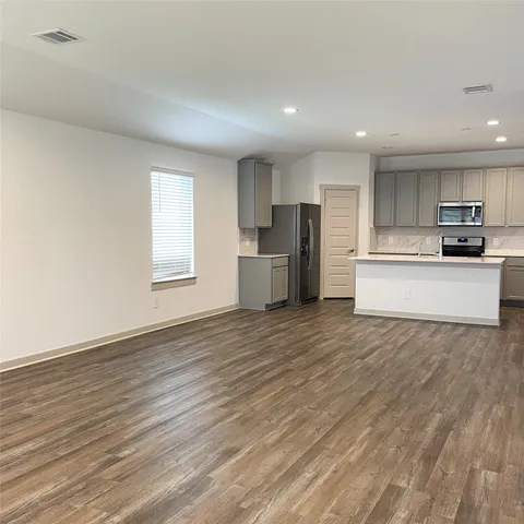 a large kitchen with a wooden floor and stainless steel appliances