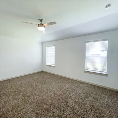 an empty room with windows and fan