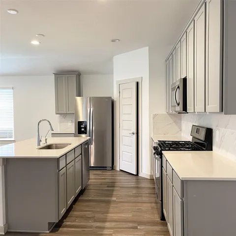 a kitchen with a sink a refrigerator a stove and a sink with wooden floor