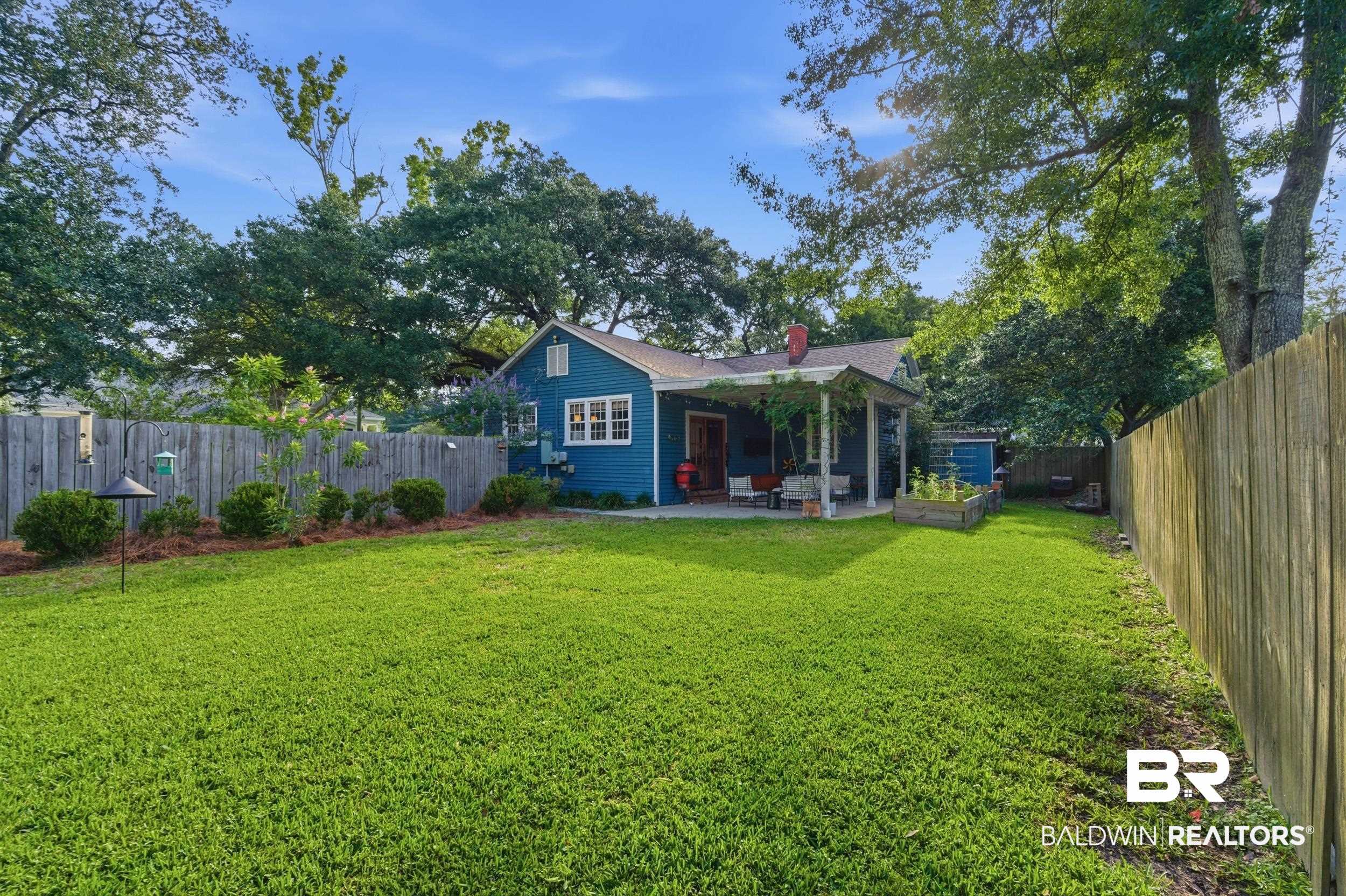 350 Charles Street Mobile, AL 36604 - Photo 33 of 52 Expansive grassy backyard featuring a blue-sided residence with white trim, a covered patio, and a privacy fence