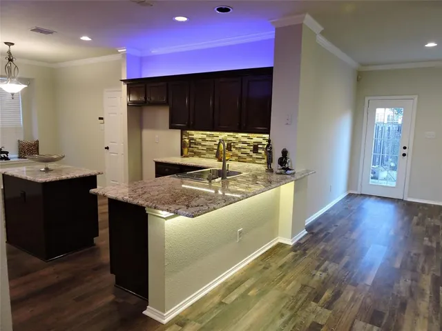 a kitchen with kitchen island granite countertop a sink and a stove top oven