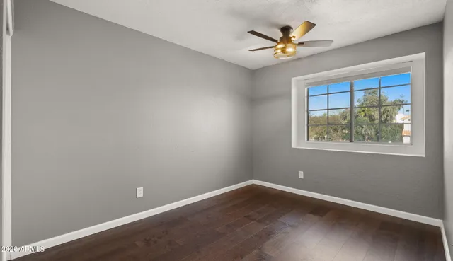 an empty room with a window and a ceiling fan