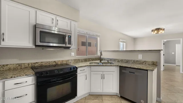 a kitchen with stainless steel appliances granite countertop a refrigerator a stove a sink and a microwave