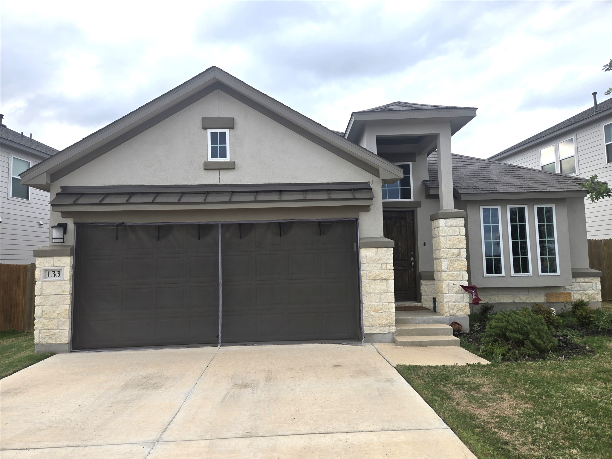 View of front of home with stone siding, stucco siding, driveway, and a garage