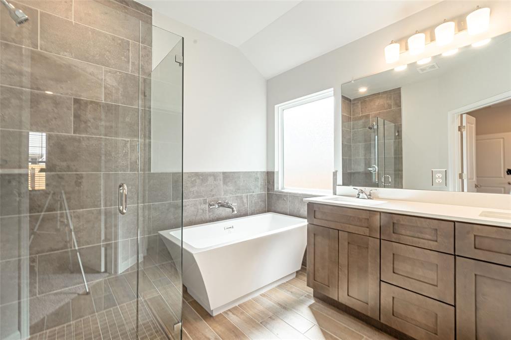 133 Boulder Ridge Trail Liberty Hill, TX 78642 - Photo 15 of 32 Bathroom featuring double vanity, a stall shower, a freestanding bath, lofted ceiling, and tile walls