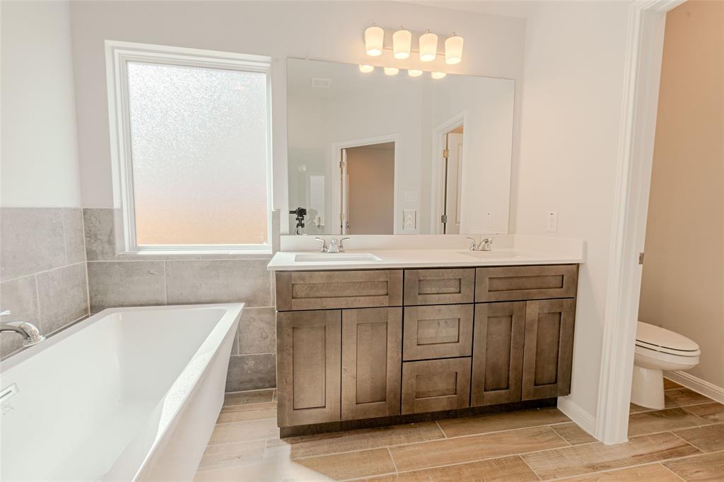 133 Boulder Ridge Trail Liberty Hill, TX 78642 - Photo 16 of 32 Bathroom with double vanity, a garden tub, and wood finish floors
