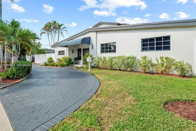 a front view of a house with a yard and potted plants