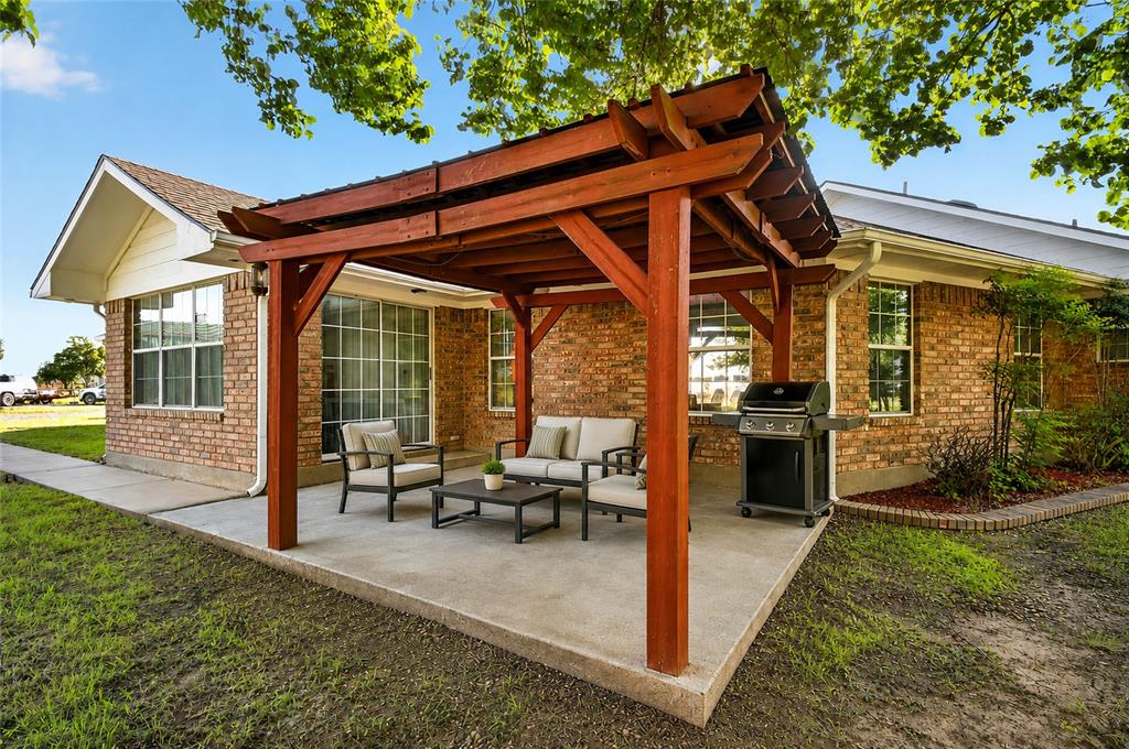 1612 Whitemound Road Sherman, TX 75090 - Photo 17 of 28 Expansive outdoor patio featuring a wooden - pergola, concrete hardscaping, brick exterior, and landscaped garden beds (Virtually Staged)