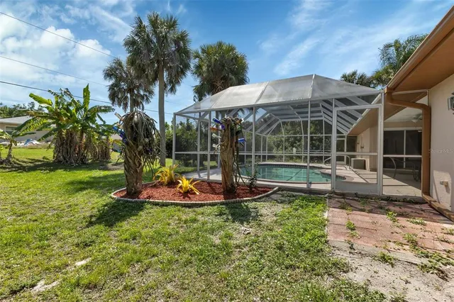 a backyard of a house with table and chairs potted plants and large tree