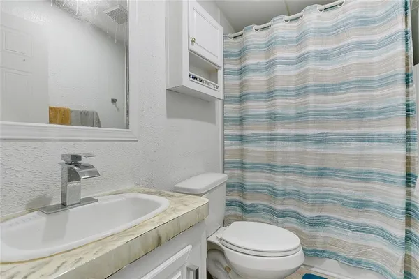 a bathroom with a sink a toilet and shower curtain