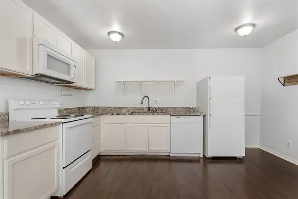 a kitchen with granite countertop white cabinets and white appliances