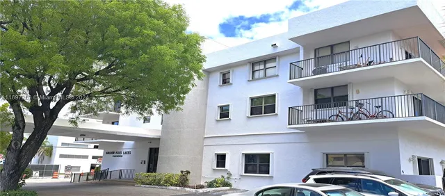 a front view of a building with lot of trees