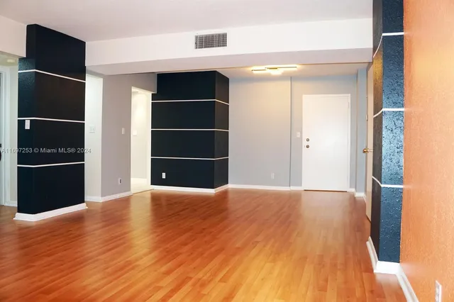 a view of an empty room with wooden floor and closet
