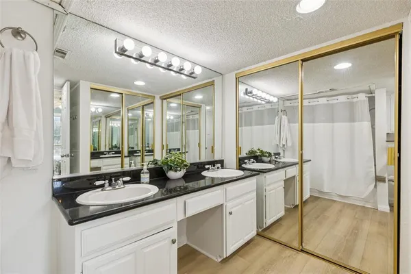 a bathroom with a double vanity sink a large mirror and shower