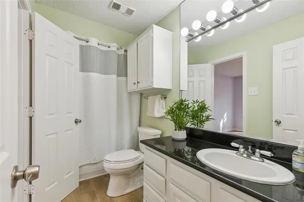 a bathroom with a granite countertop sink a toilet and a mirror