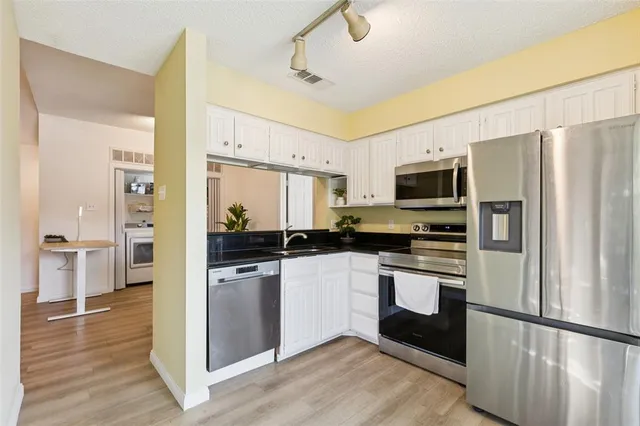 a kitchen with stainless steel appliances granite countertop a refrigerator a stove top oven a sink and dishwasher
