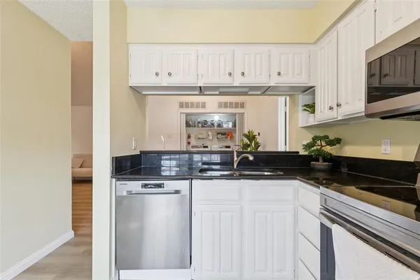 a kitchen with granite countertop a sink a stove and cabinets