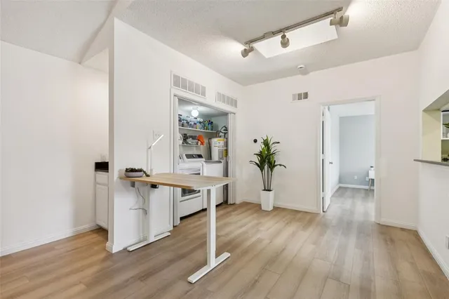 a view of a hallway to a livingroom with wooden floor and furniture