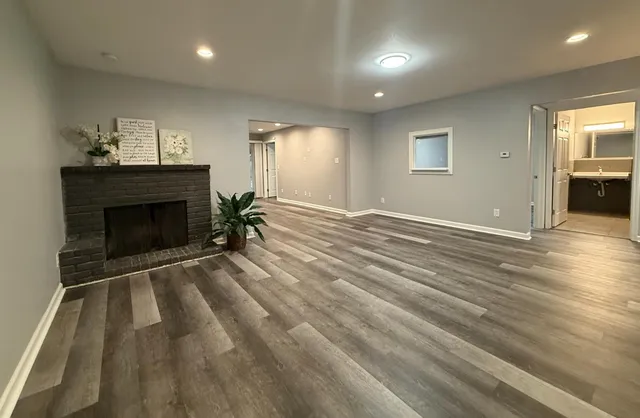 an empty room with wooden floor fireplace and windows