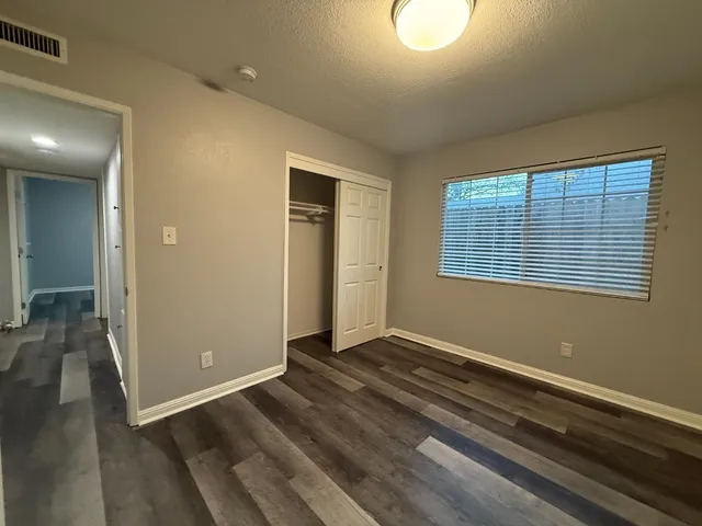 an empty room with wooden floor and windows
