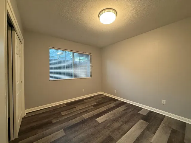 an empty room with wooden floor and windows