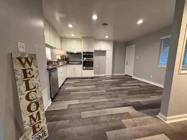 a large white kitchen with wooden floors and stainless steel appliances