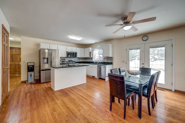 a kitchen with stainless steel appliances kitchen island granite countertop a table chairs refrigerator and microwave