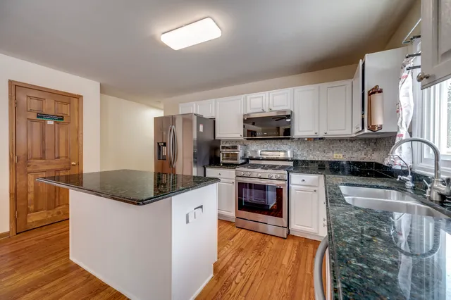 a kitchen with stainless steel appliances granite countertop a sink stove and refrigerator