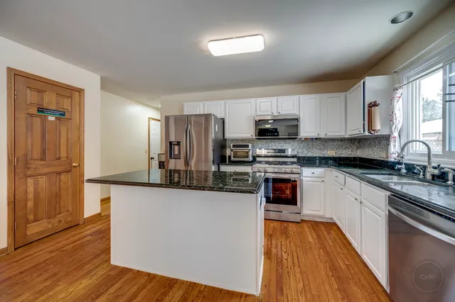 a kitchen with stainless steel appliances granite countertop a stove top oven a sink and dishwasher with wooden floor