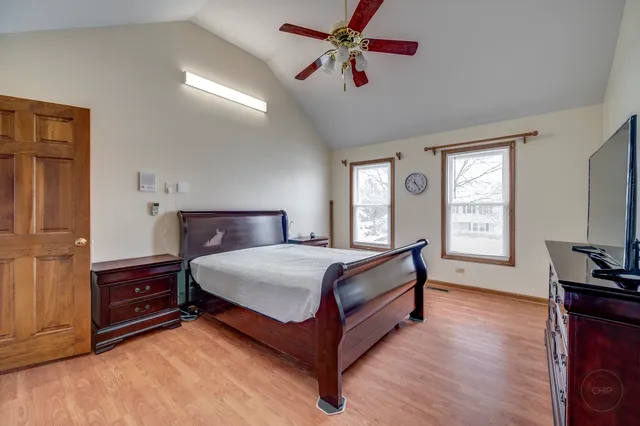 a spacious bedroom with a bed and a flat tv screen on dresser