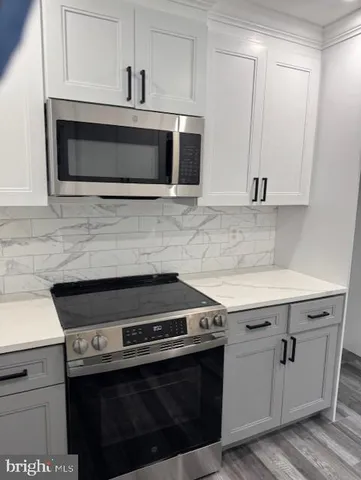 a kitchen with stainless steel appliances granite countertop white cabinets a microwave oven and a sink