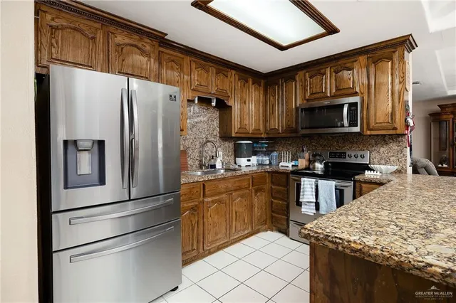 a kitchen with granite countertop a refrigerator stove and microwave